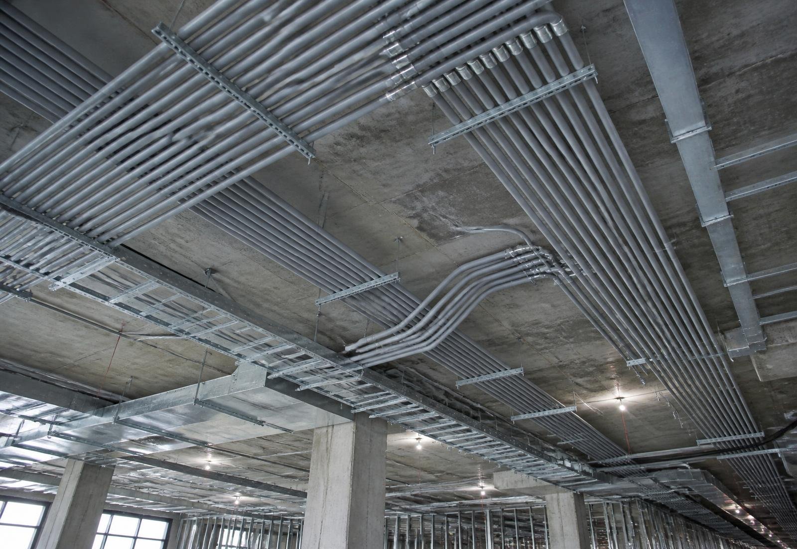Grey conduit and cable tray runs installed across a commercial building ceiling